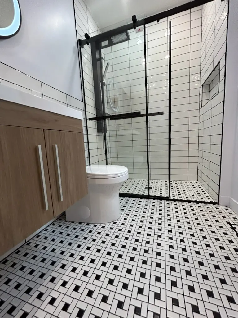 Salle de bain avec carrelage noir et blanc et douche vitrée, par Rénovations CTR